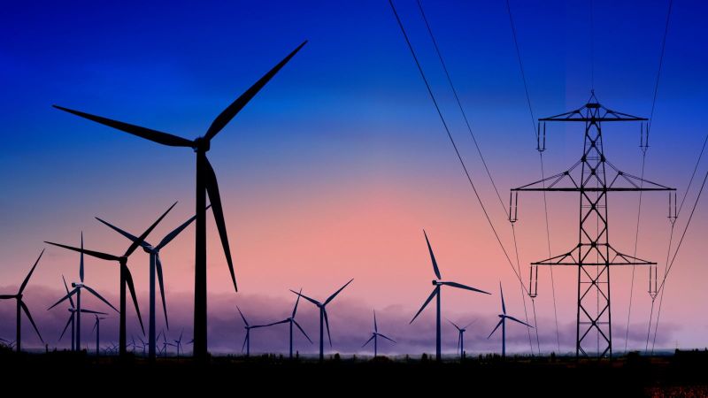 Das Bild zeigt Windräder und Stromtrassen vor dem Abendhimmel.