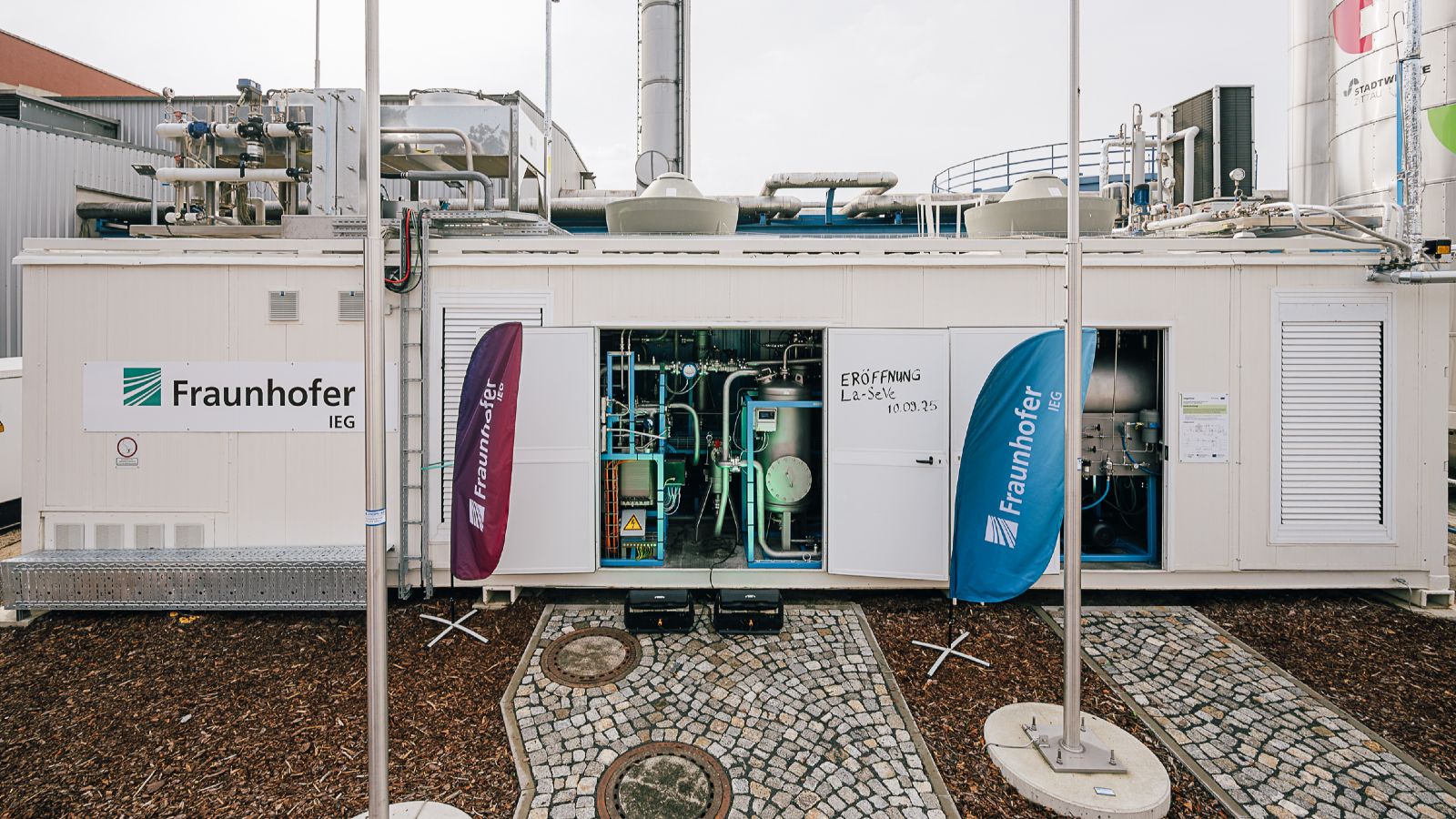 Das Bild zeigt die Laboranlage, bestehend aus einem großen Container, der auf dem Betriebsgelände der Stadtwerke Zittau steht.