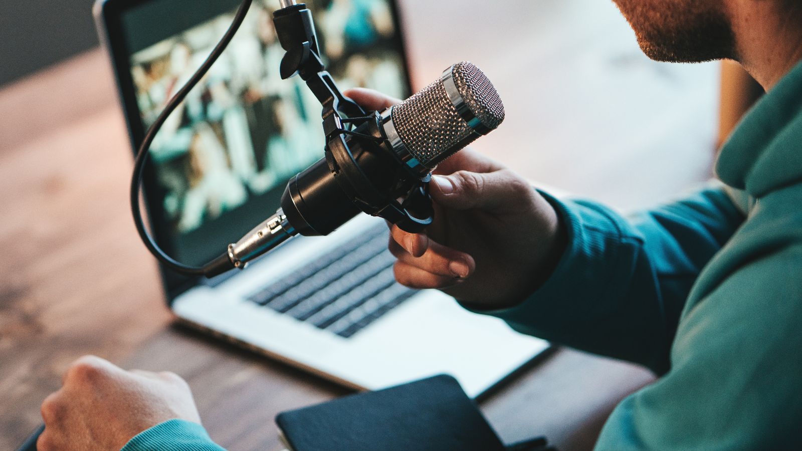 Ein Mann nutzt ein Mikrofon und Laptop für die Teilnahme an einer Online-Konferenz