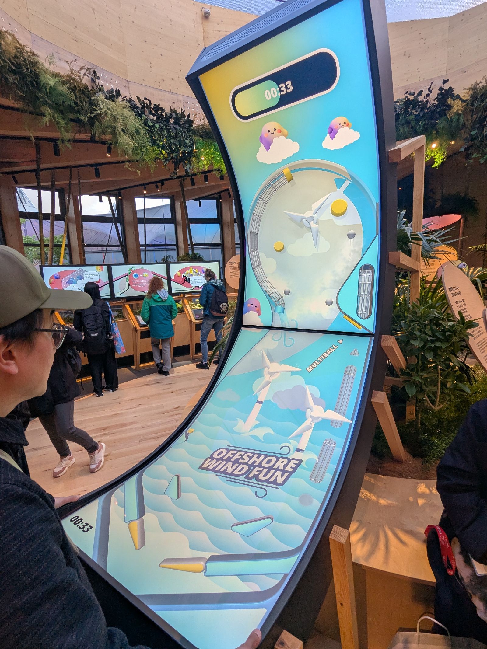 Das Bild zeigt das Exponat der Wasserstoff-Leitprojekte, mit einem Besucher als Spieler am Flipperautomaten. 